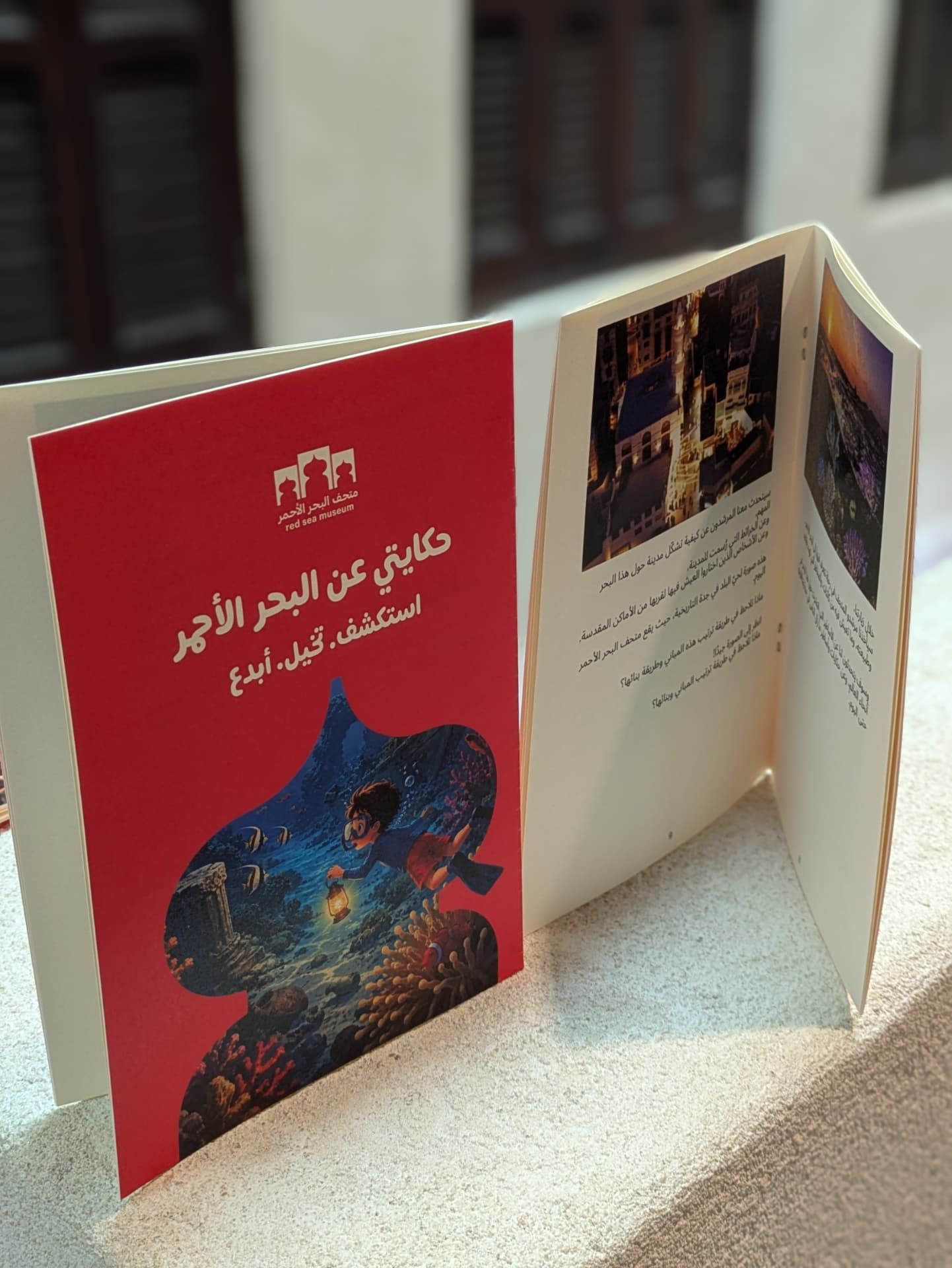 Inside pages of the Arabic edition of My Red Sea Story with a child’s writing and illustration