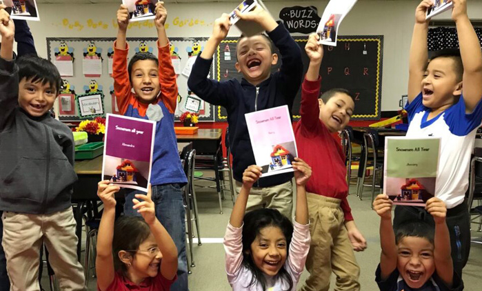 A group of young students proudly holding up the storybooks they made