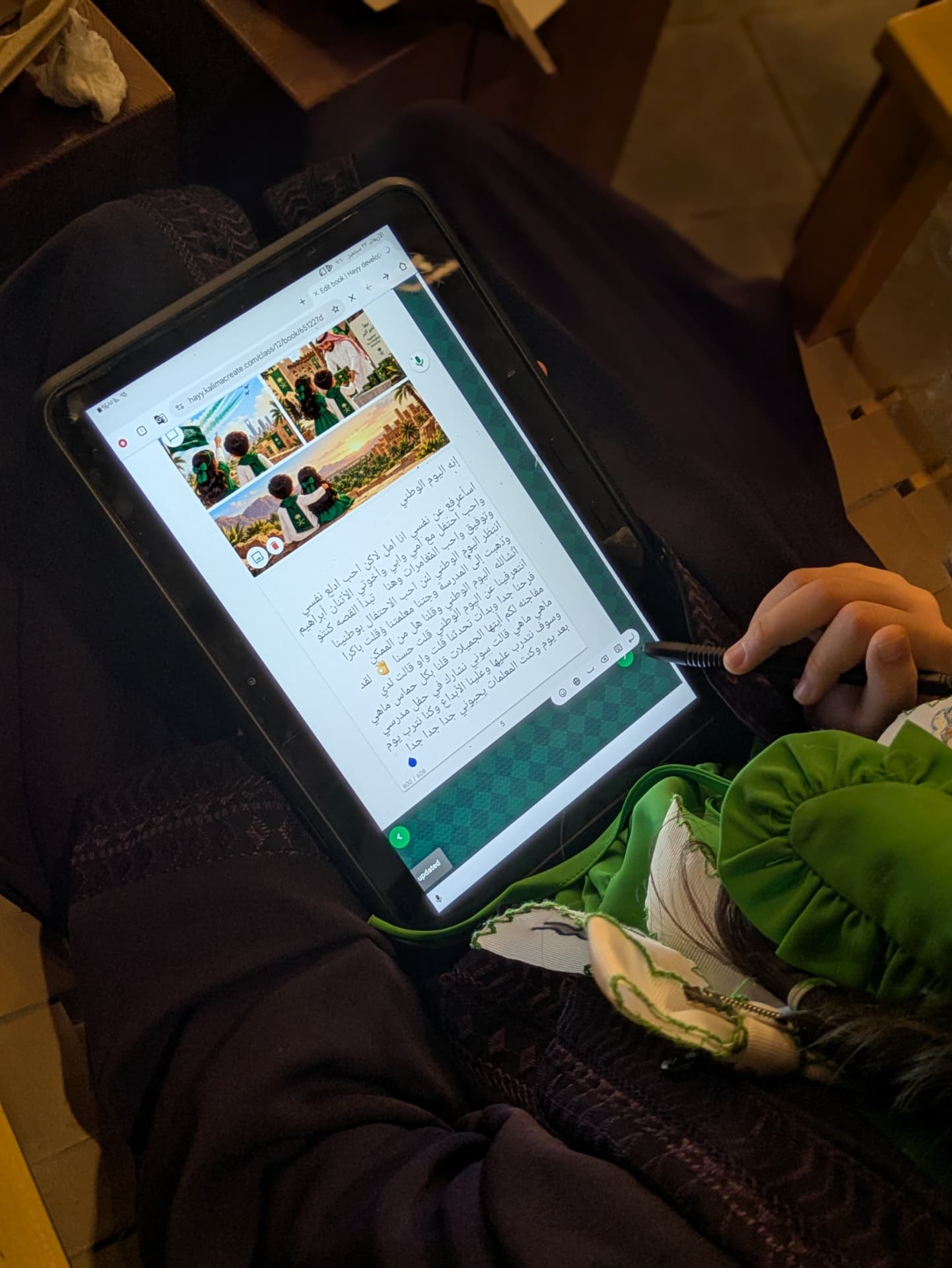 A child typing an Arabic story on a tablet with a stylus during the Al Madinah workshop